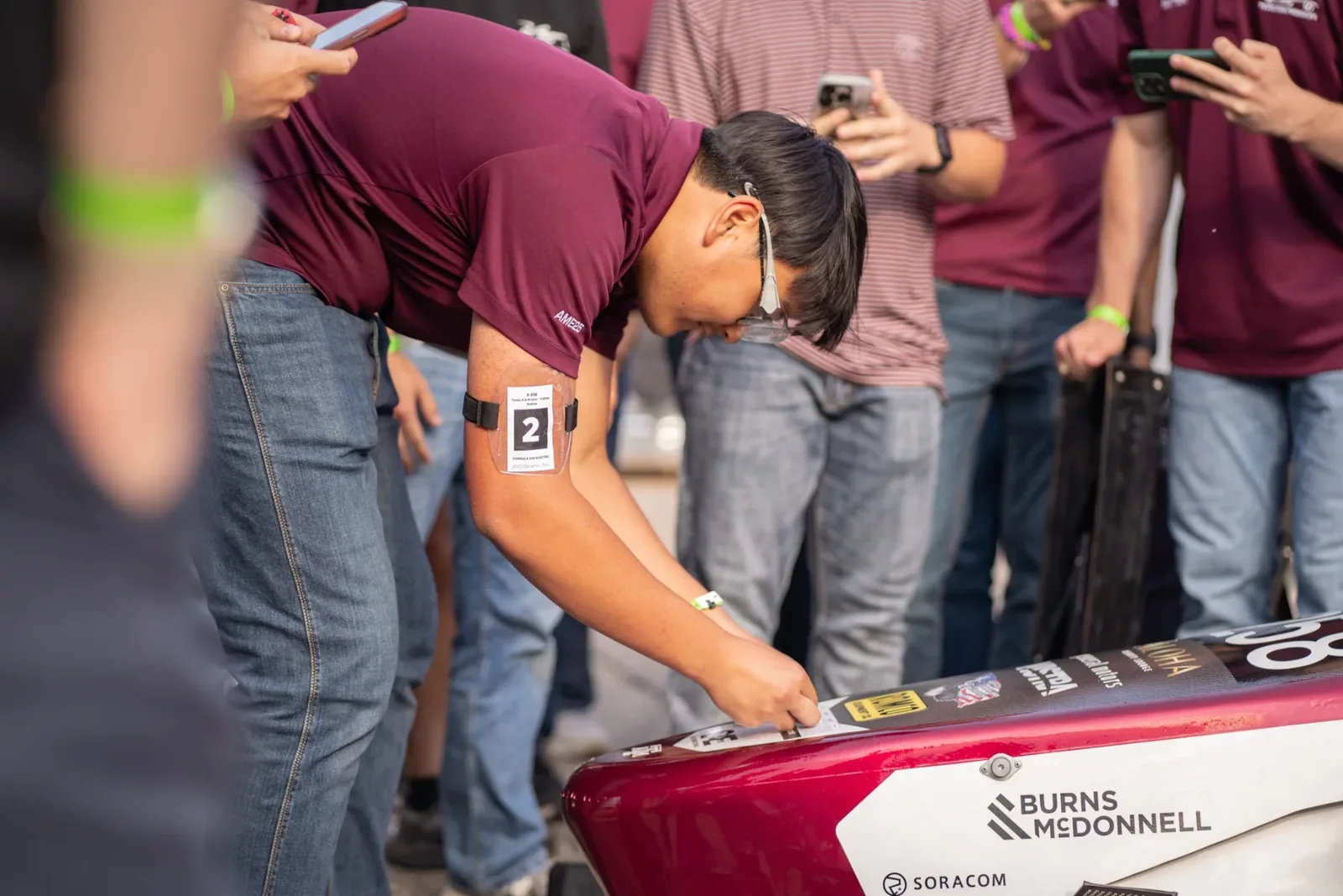 A team member signing the car’s bodywork as a crowd watches