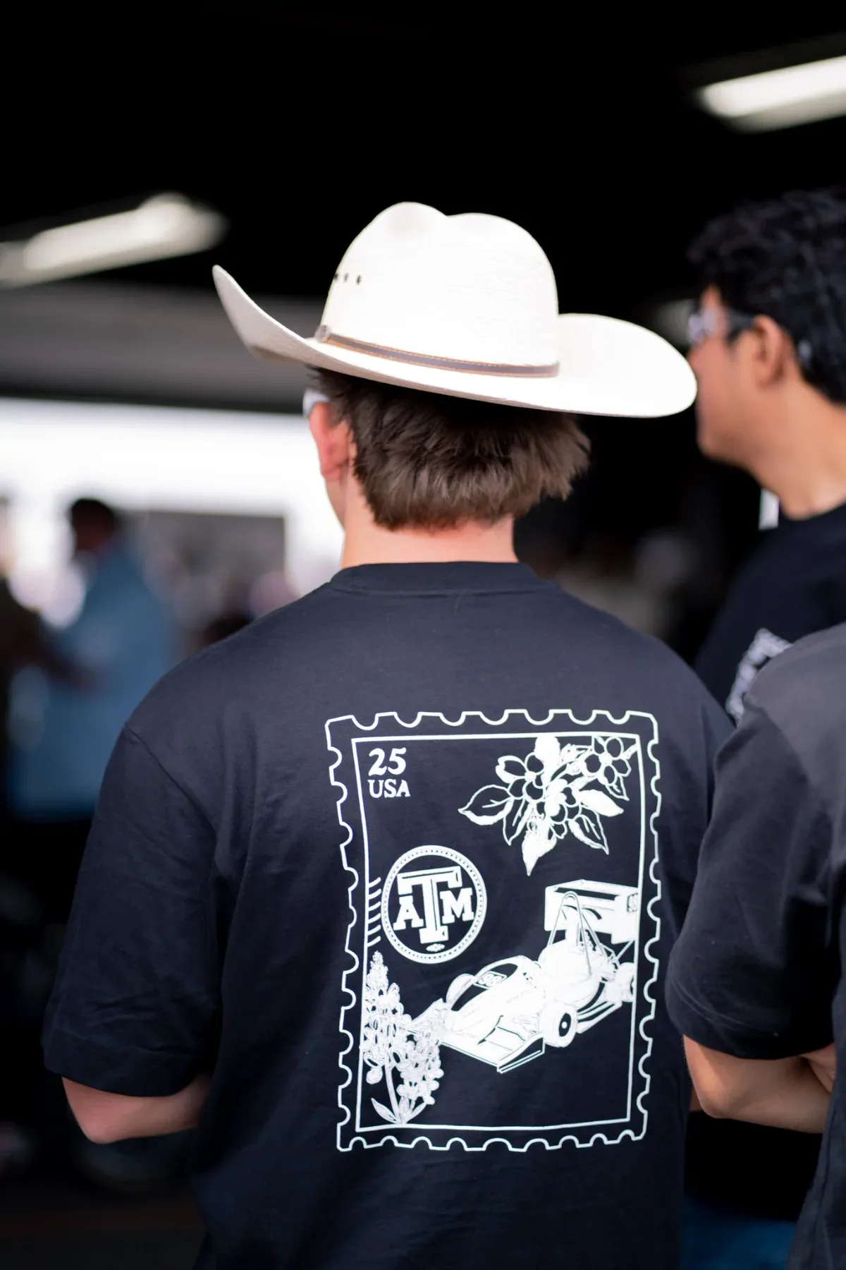 Back of a black team shirt with a stamp-style race car graphic