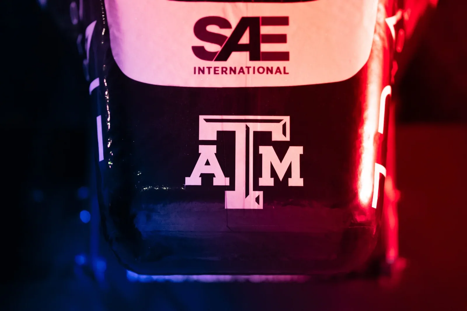 SAE and Texas A&M logos on the nose under red and blue light
