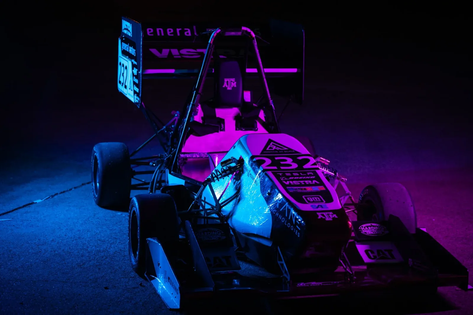 The car lit in purple and blue studio light