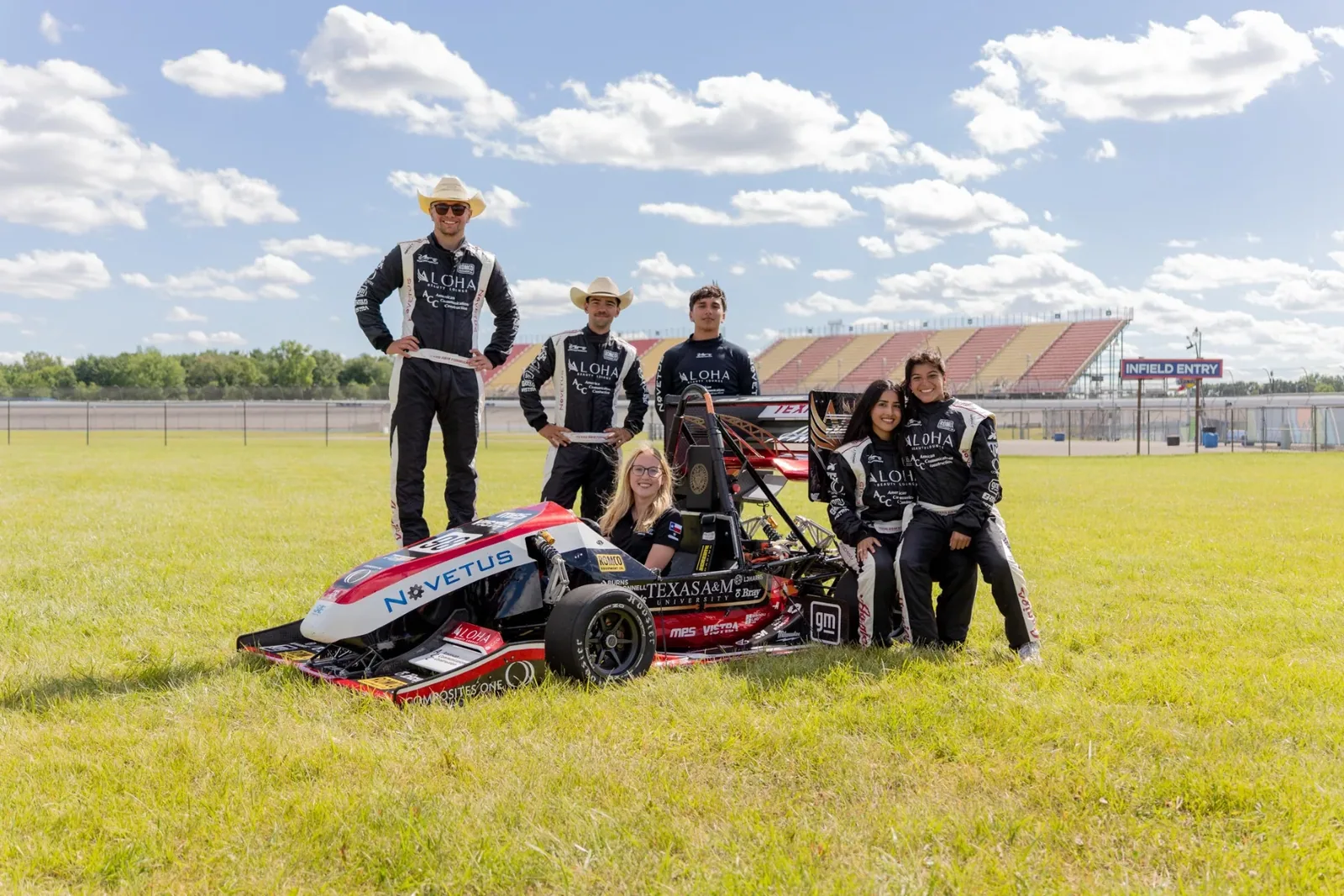Drivers in custom race suits standing with the car on the grass