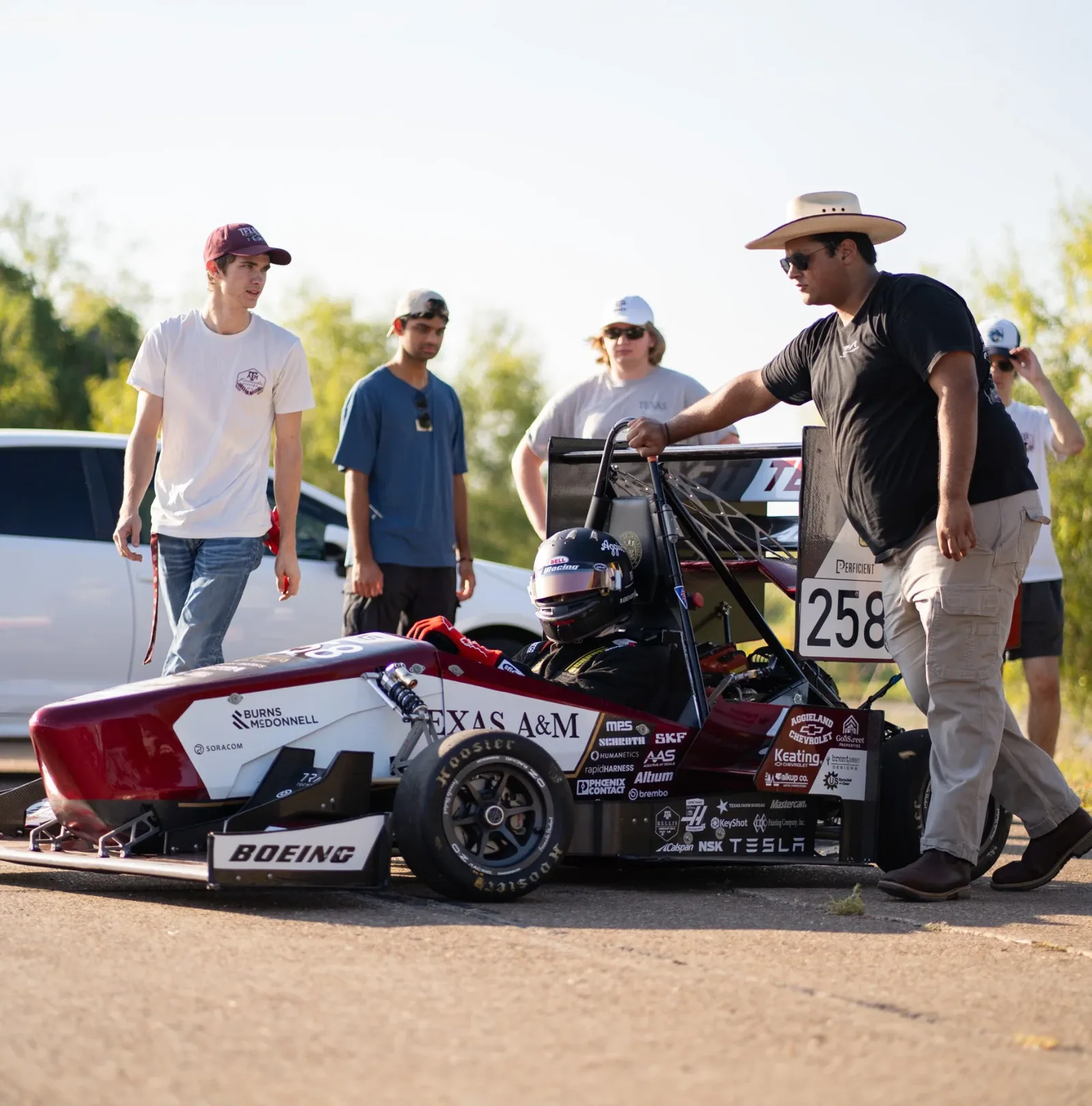 Team members gathered around AEM25 in a parking lot