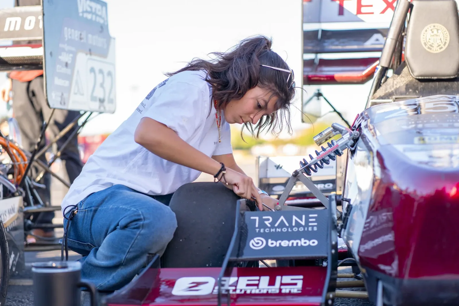 A team member kneeling to work on the side of the car