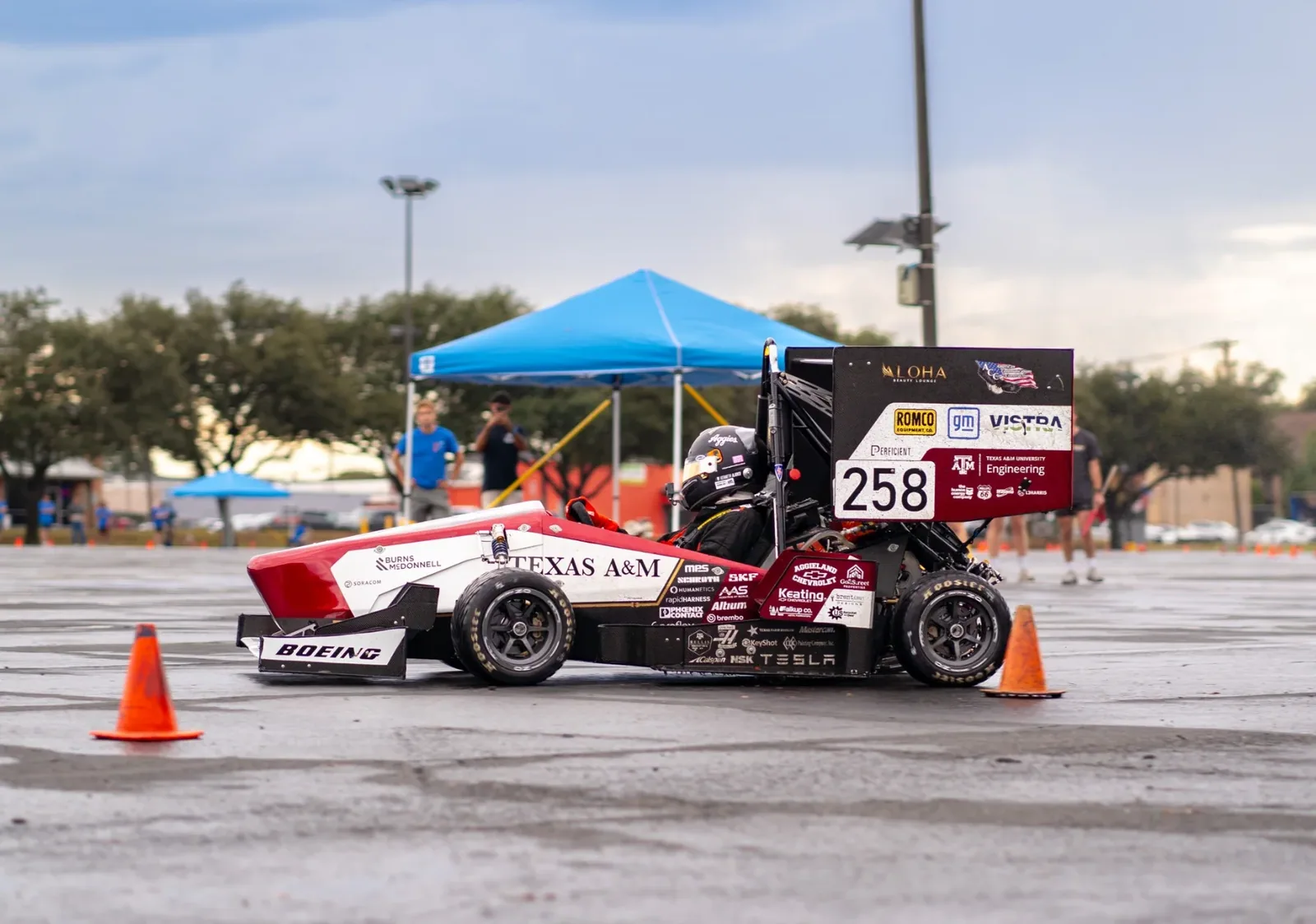 Car 258 rounding cones in a parking lot beside a blue tent